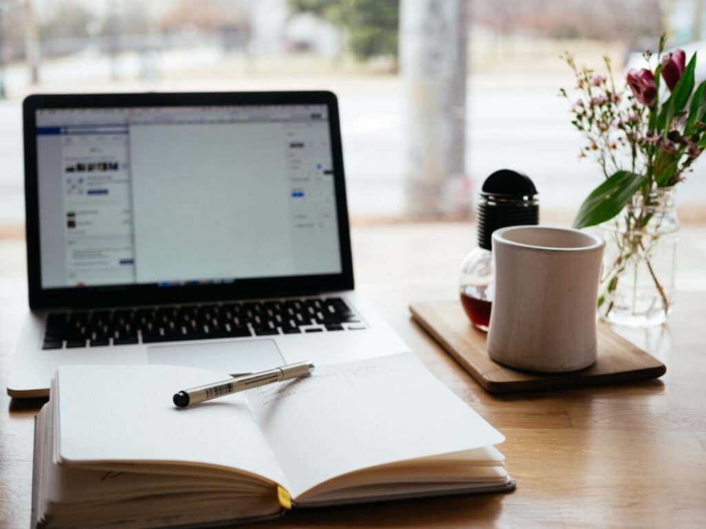Laptop, notebook and pens on a desk for planning a WordPress website project